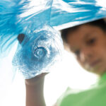 Muovinkierrätys alkaa kotitalouksista, poika laittaa muovipulloa muovipussiin.